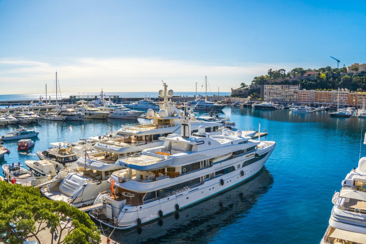 Monaco Yacht Show 2026 Travel Guide: Transport Between Marinas, Hotels, airports & Events 1 Luxury yachts docked in a sunny harbor with blue water.