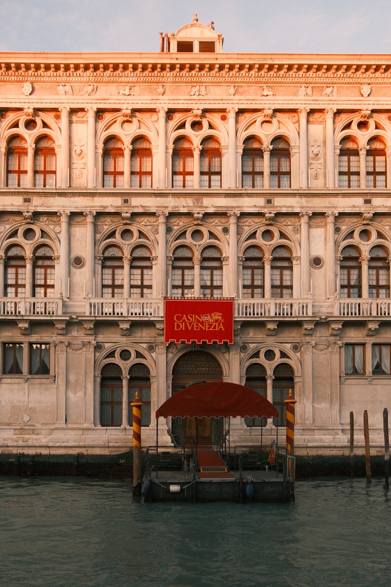 The Best Luxury Casinos in Europe for High-End Travellers 5 Ornate venetian building with red banner above entrance.