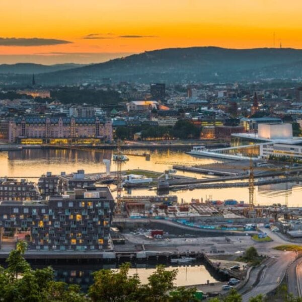 Blue chrome skies and orange glow of midsummer sunset over the iconic landmarks and waterfront of central Oslo to the forested hills of southern Norway beyond. ProPhoto RGB profile for maximum color fidelity and gamut.