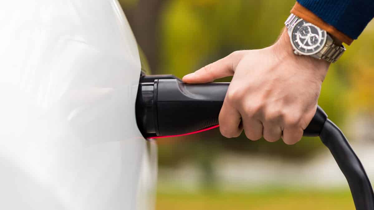 close view man plugging charger into electric car charging port